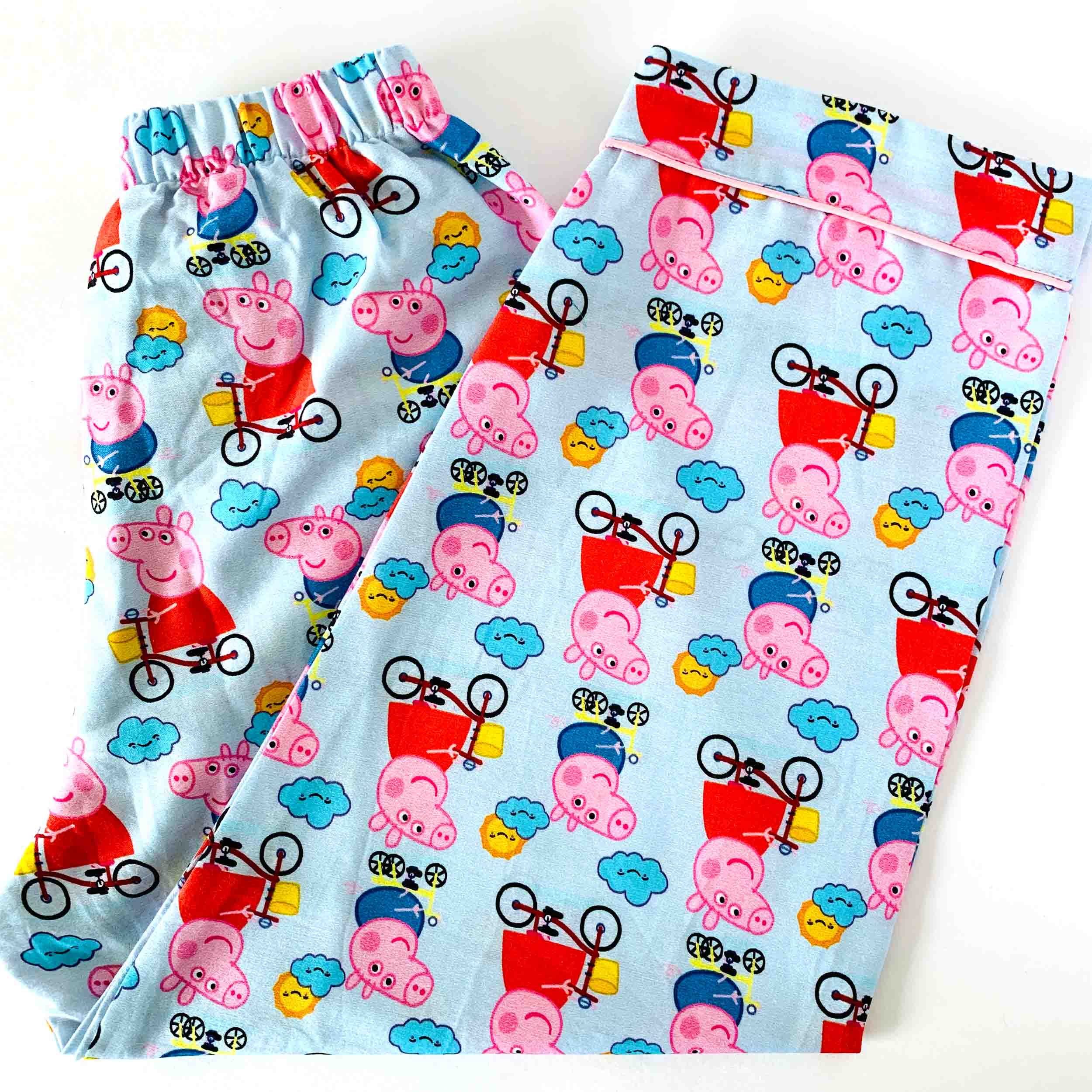 Children's pajama pants with Peppa Pig pattern on a light blue background