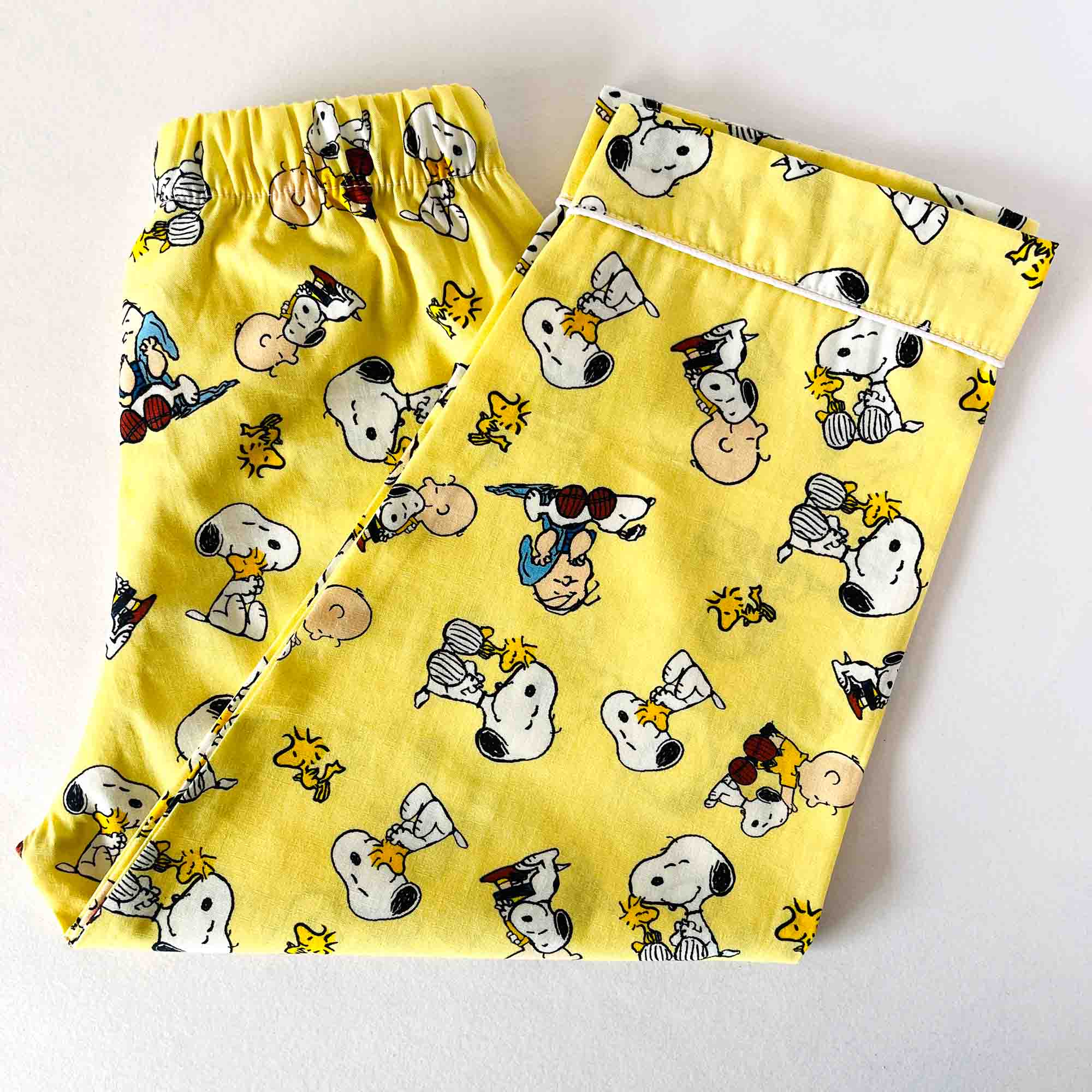 Yellow pajama pants with cartoon character pattern on a white background