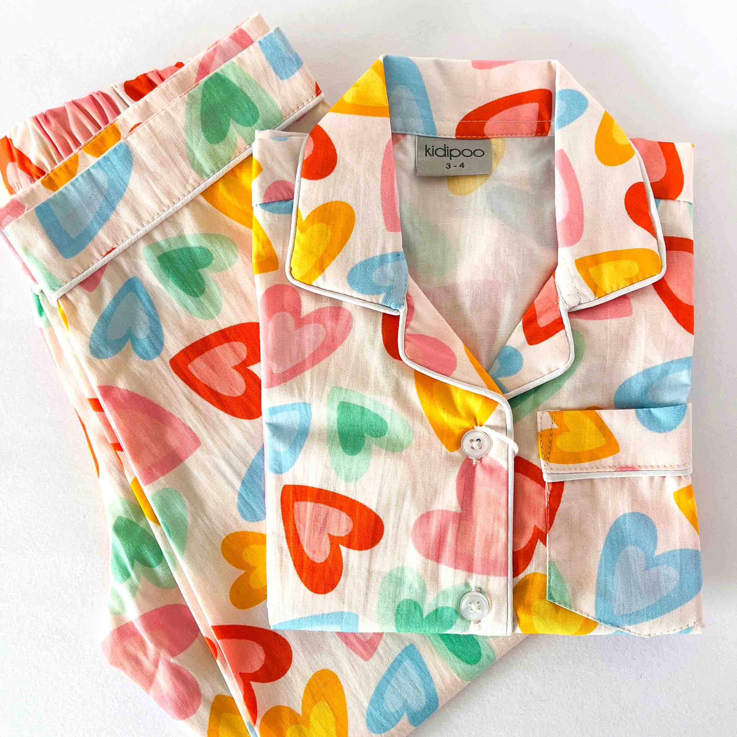 Colorful heart-patterned pajama set with 'kidpoo' branding on a white background