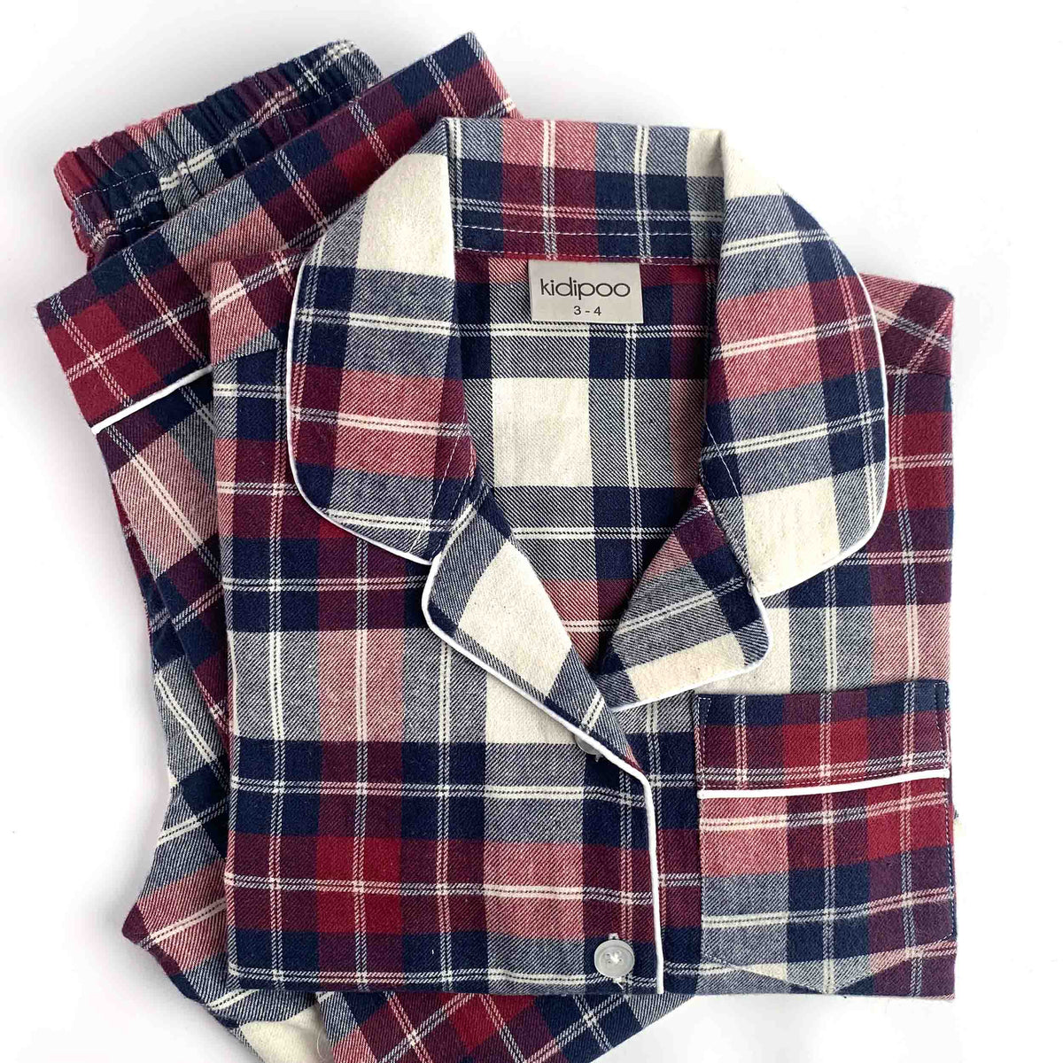 A folded plaid pajama set with a long-sleeve button-front top and matching pants, shown on a clean white background. The fabric has a classic tartan pattern in navy blue, burgundy red, and cream, with white piping along the collar and placket.