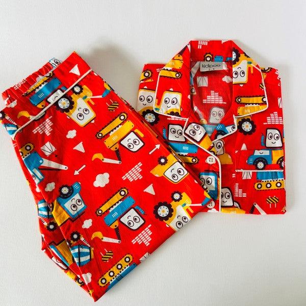 A red and blue baby night suit with a truck pattern, consisting of a long sleeve shirt and pants.