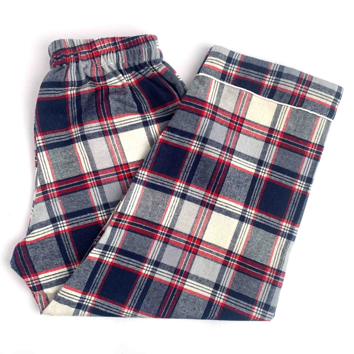 A pair of plaid lounge pants folded on a white background, featuring a navy, red, and white tartan pattern.