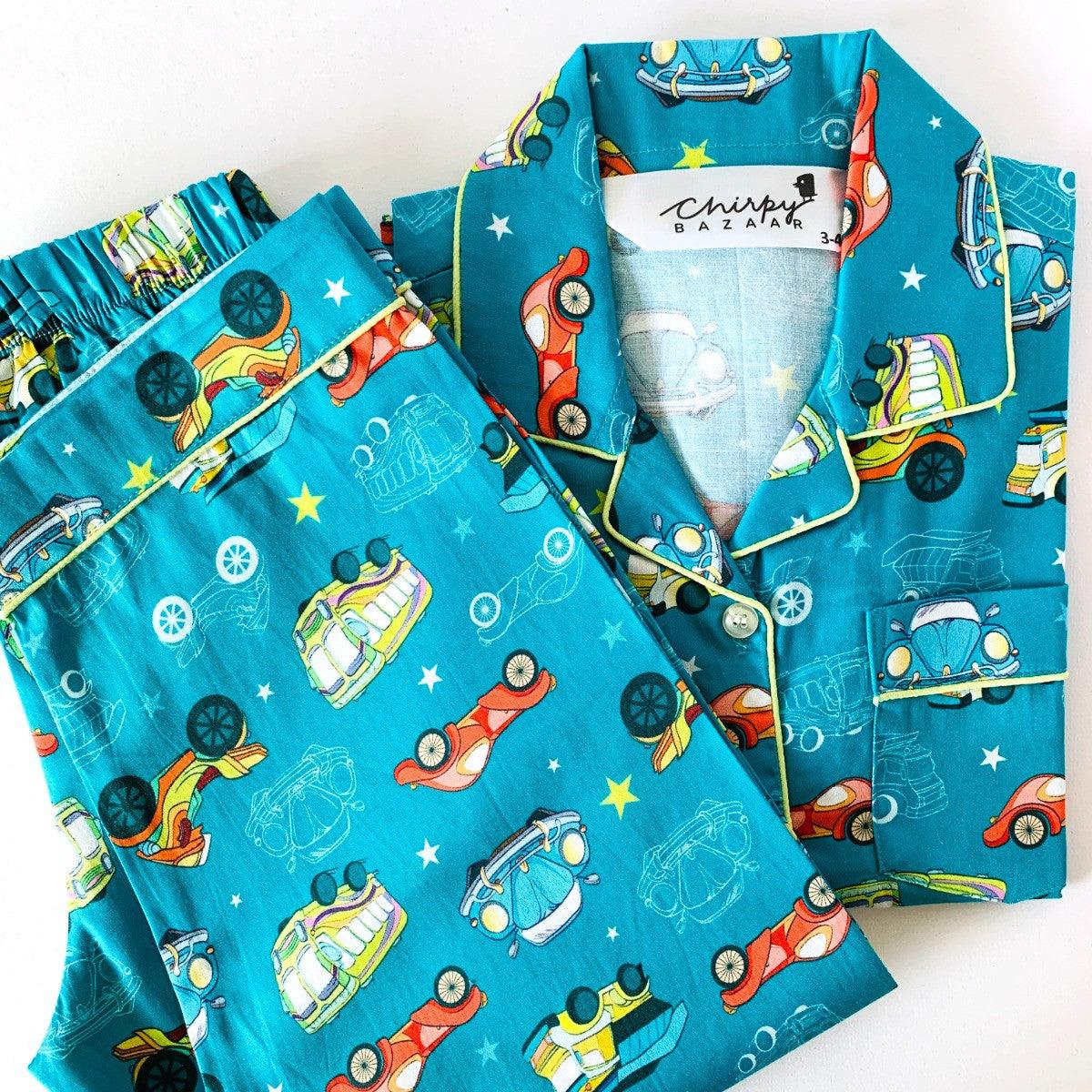 A set of children's sleepwear featuring a blue background with retro style cars and stars, including a long sleeve shirt and pajamas with elastic at waist