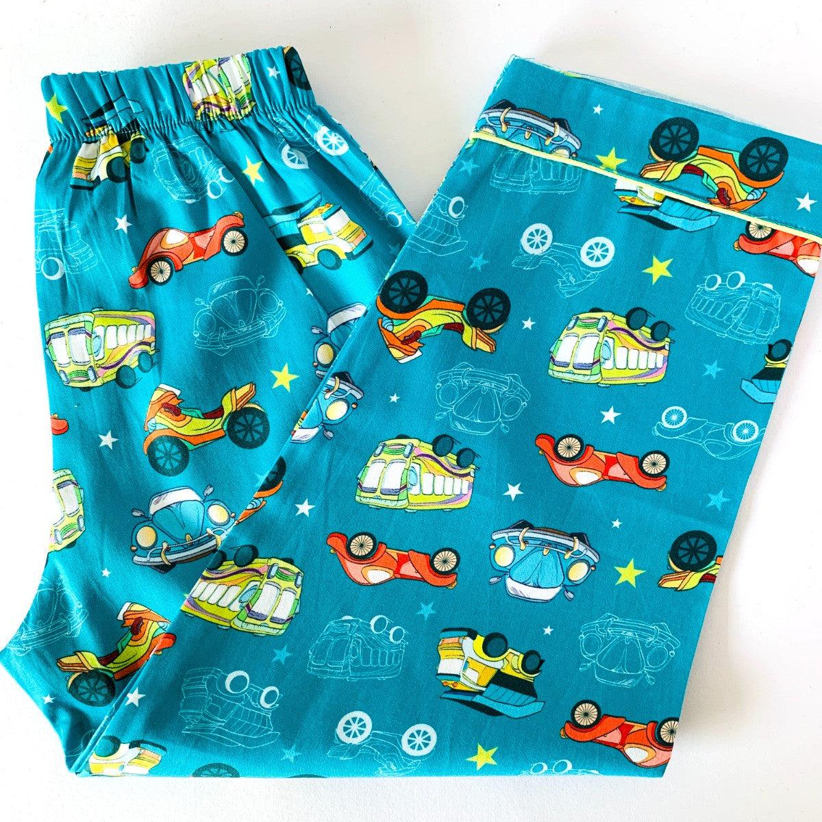 A set of children's sleepwear featuring a blue background with retro style cars and stars, including a long sleeve shirt and pajamas with elastic at waist.