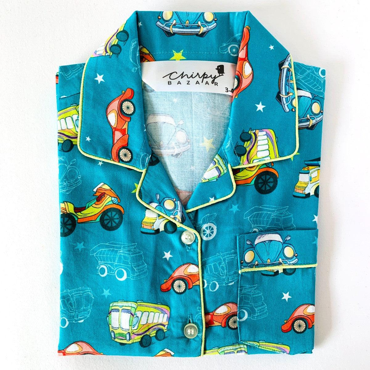 A set of children's sleepwear featuring a blue background with retro style cars and stars, including a long sleeve shirt and pajamas with elastic at waist.
