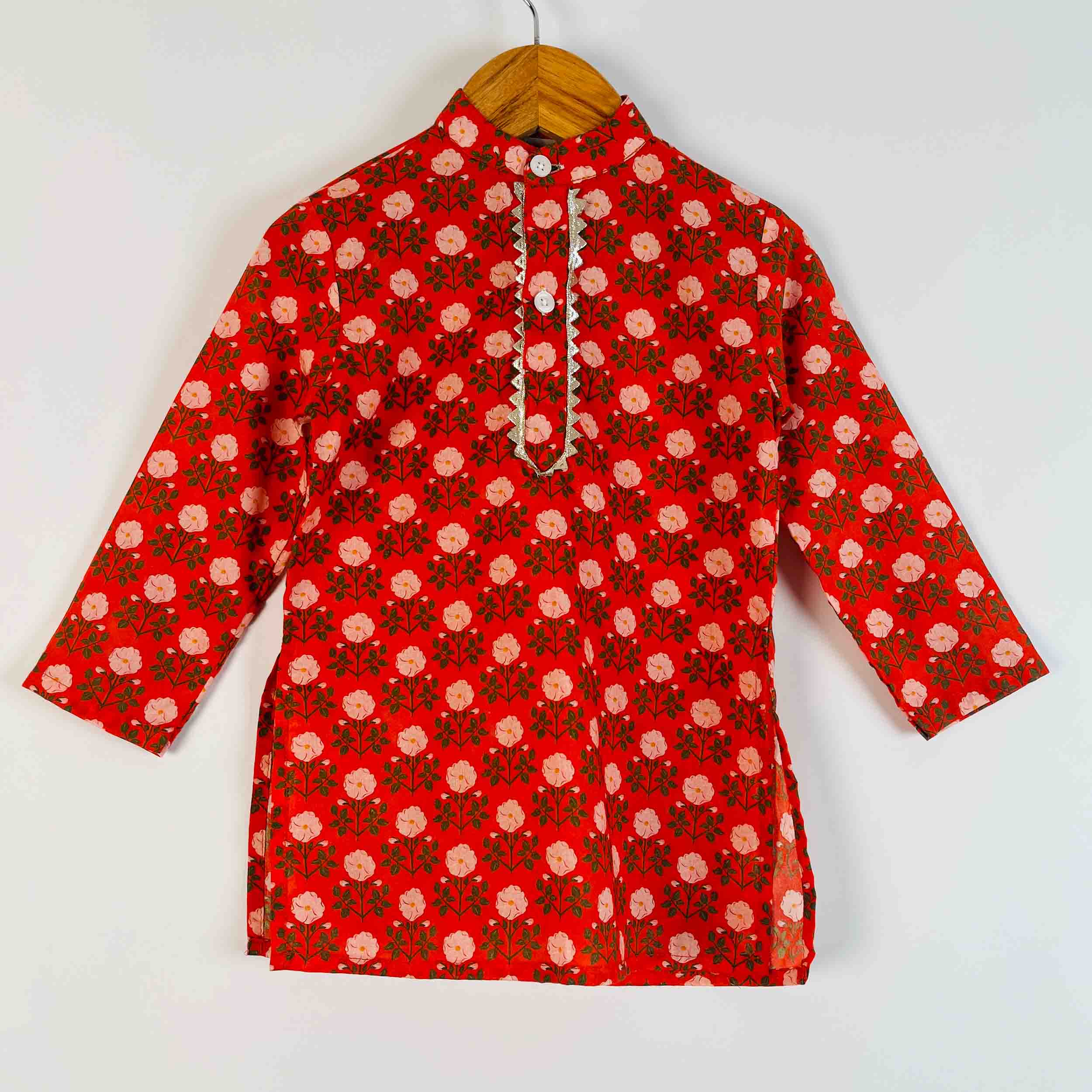 A red long-sleeve kurta with a repeating pink and green floral block print, hanging on a wooden hanger against a plain white background.