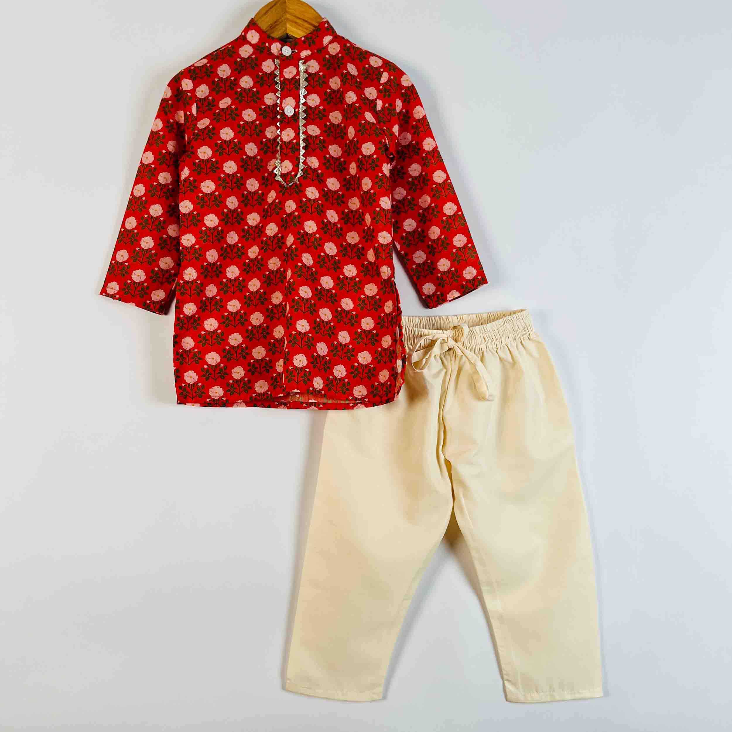 A two-piece children's outfit set consisting of a red long-sleeve kurta with a white floral pattern and beige drawstring pants, displayed on a hanger against a light gray background.