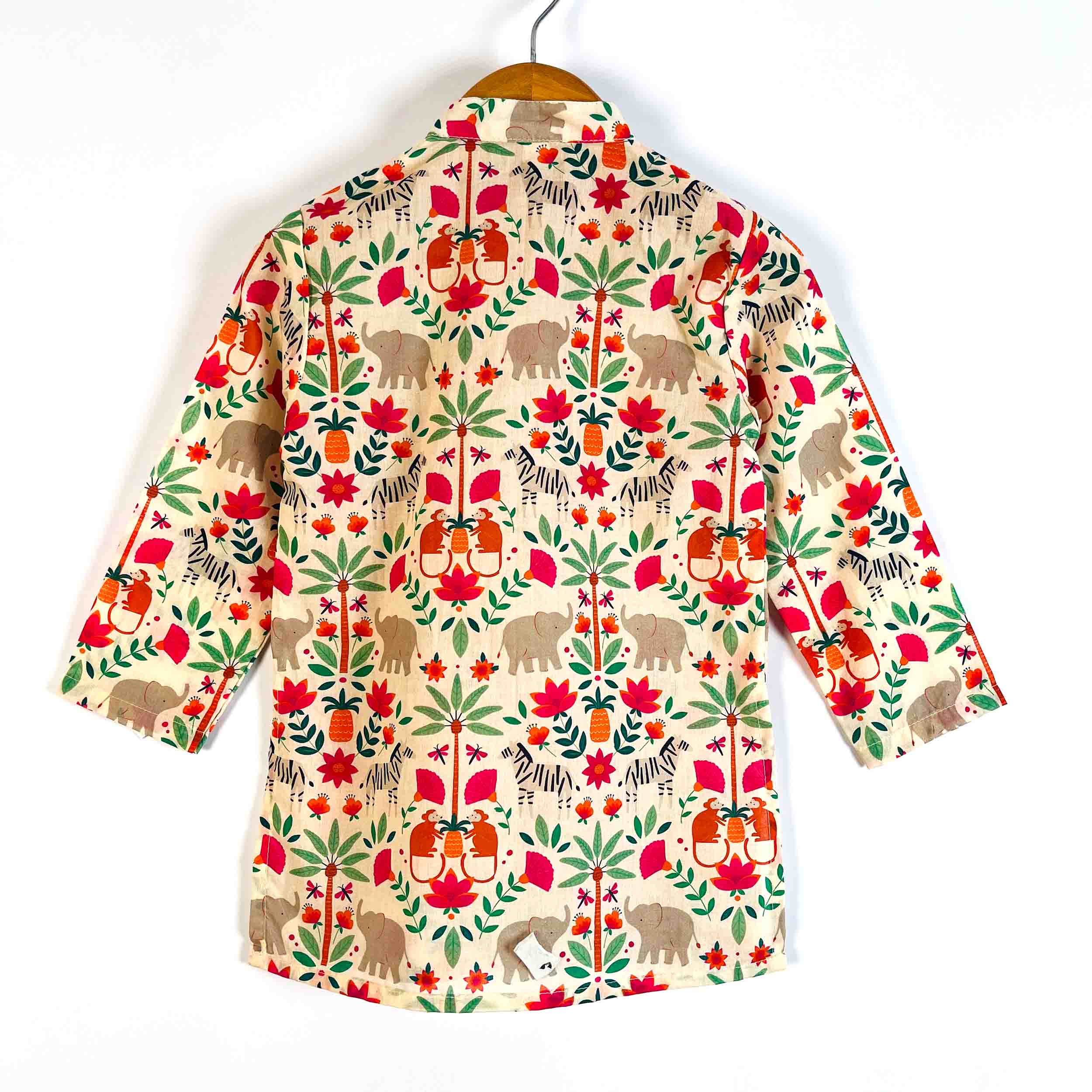 A long-sleeve button-up shirt with a colorful elephant and floral pattern, hanging on a wooden hanger against a plain white background.
