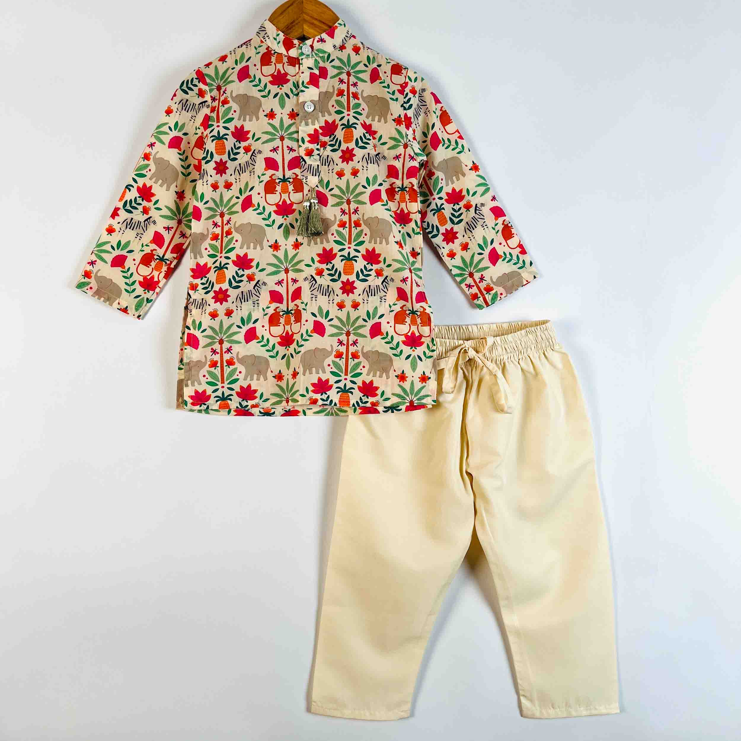 A children's two-piece outfit set consisting of a long-sleeve top with a colorful animal and floral print on a cream base, paired with cream-colored pants with an elastic waist and drawstring, displayed on a hanger against a plain white background.