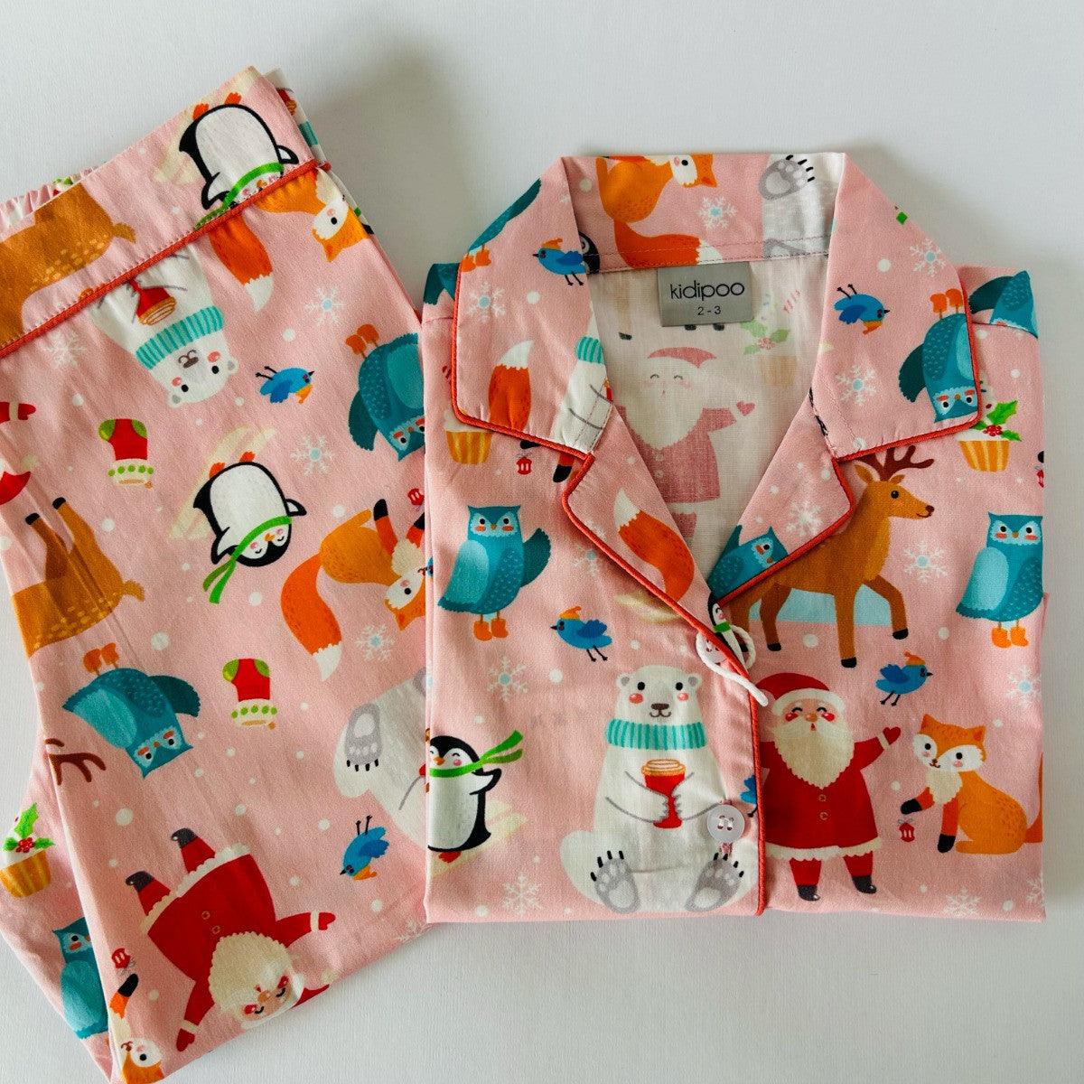 A pink night suit with a Christmas theme, featuring illustrations of Santa, reindeer, and snowflakes.
