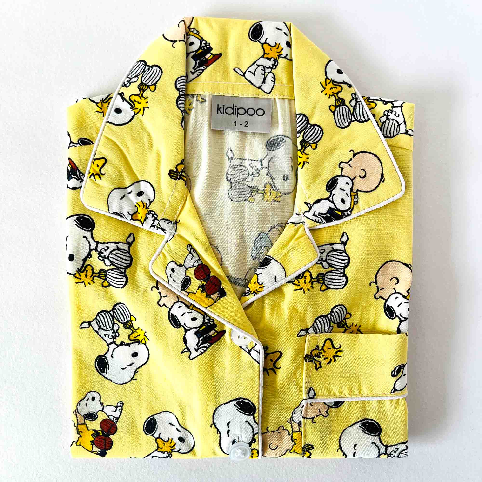 Yellow children's pajama set with Snoopy and Woodstock pattern on a white background