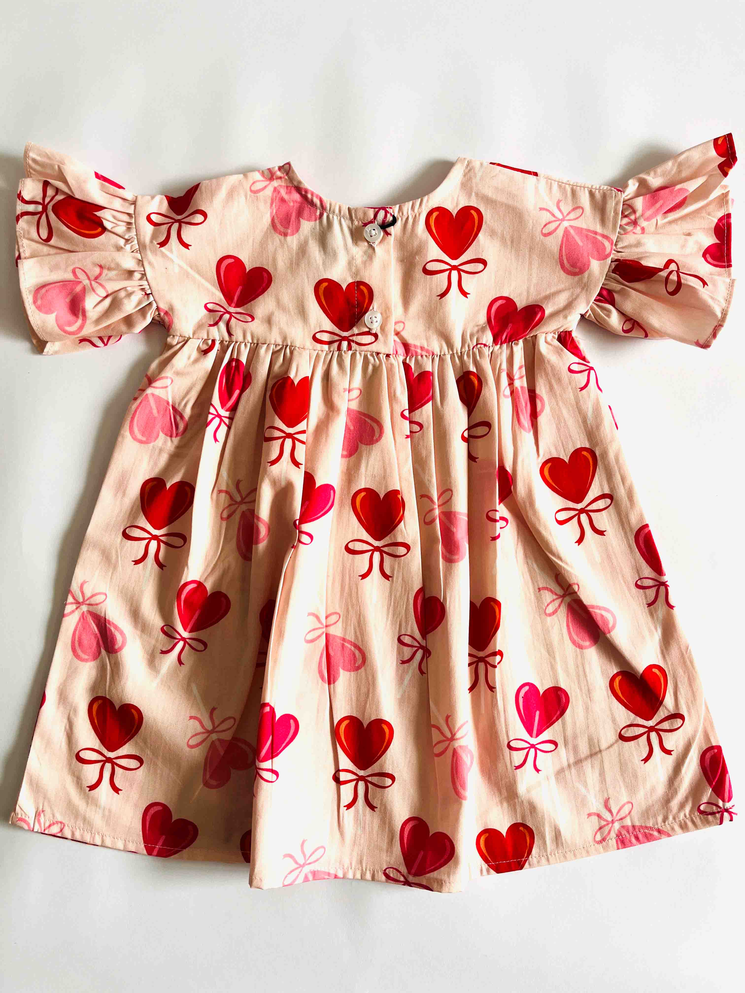 Children's dress with heart and bow pattern on a white background