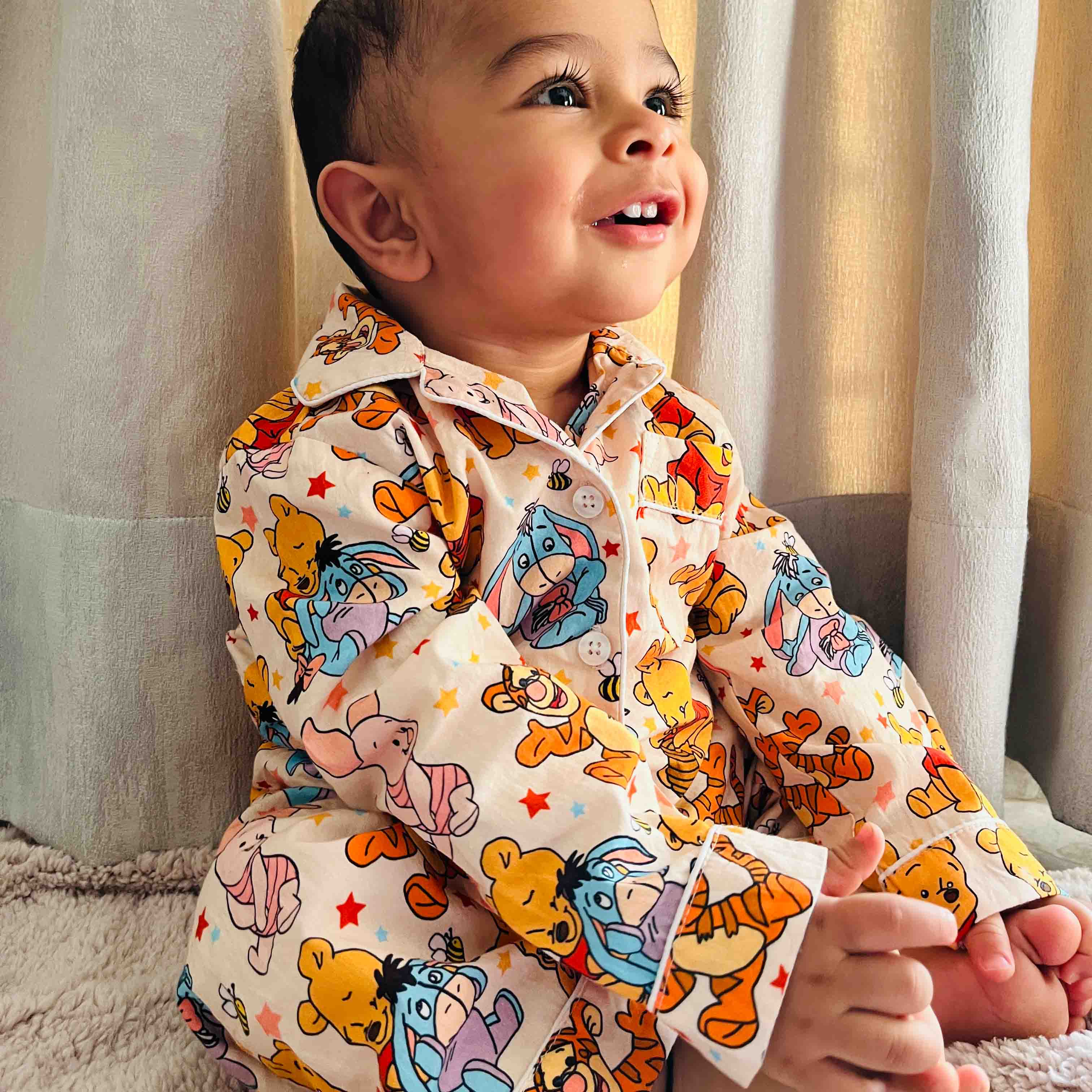 Child wearing a colorful cartoon-themed shirt sitting on a couch.